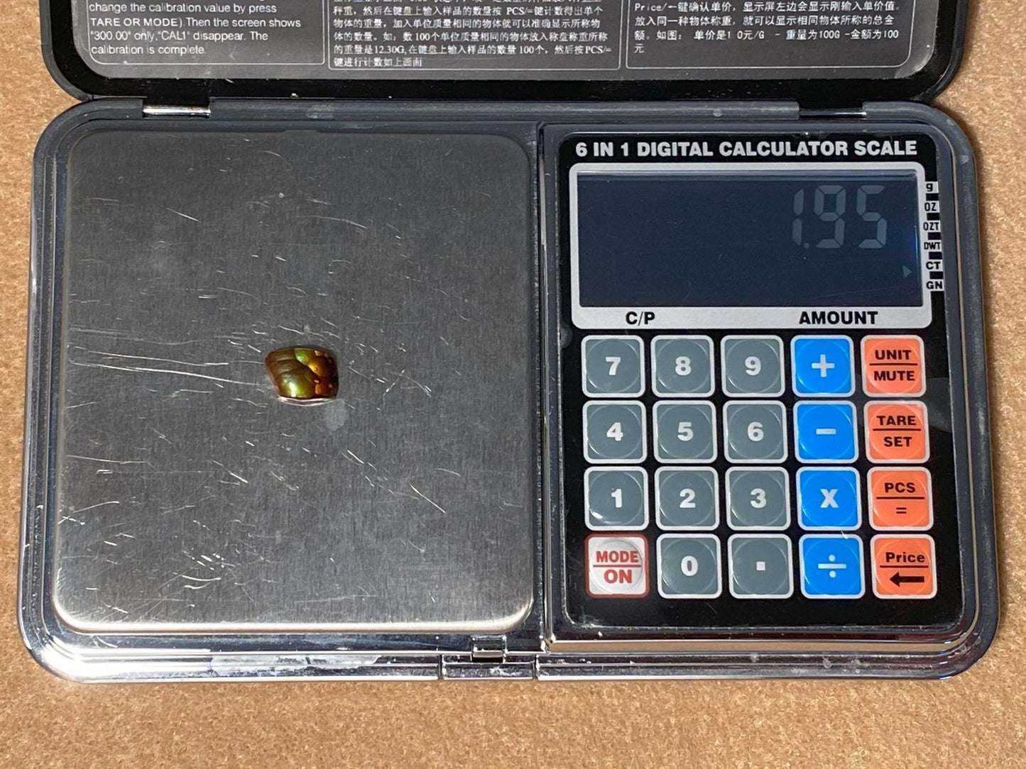 Digital calculator scale with a Deer Creek fire agate gemstone on it, displaying a weight reading of 1.95 carats