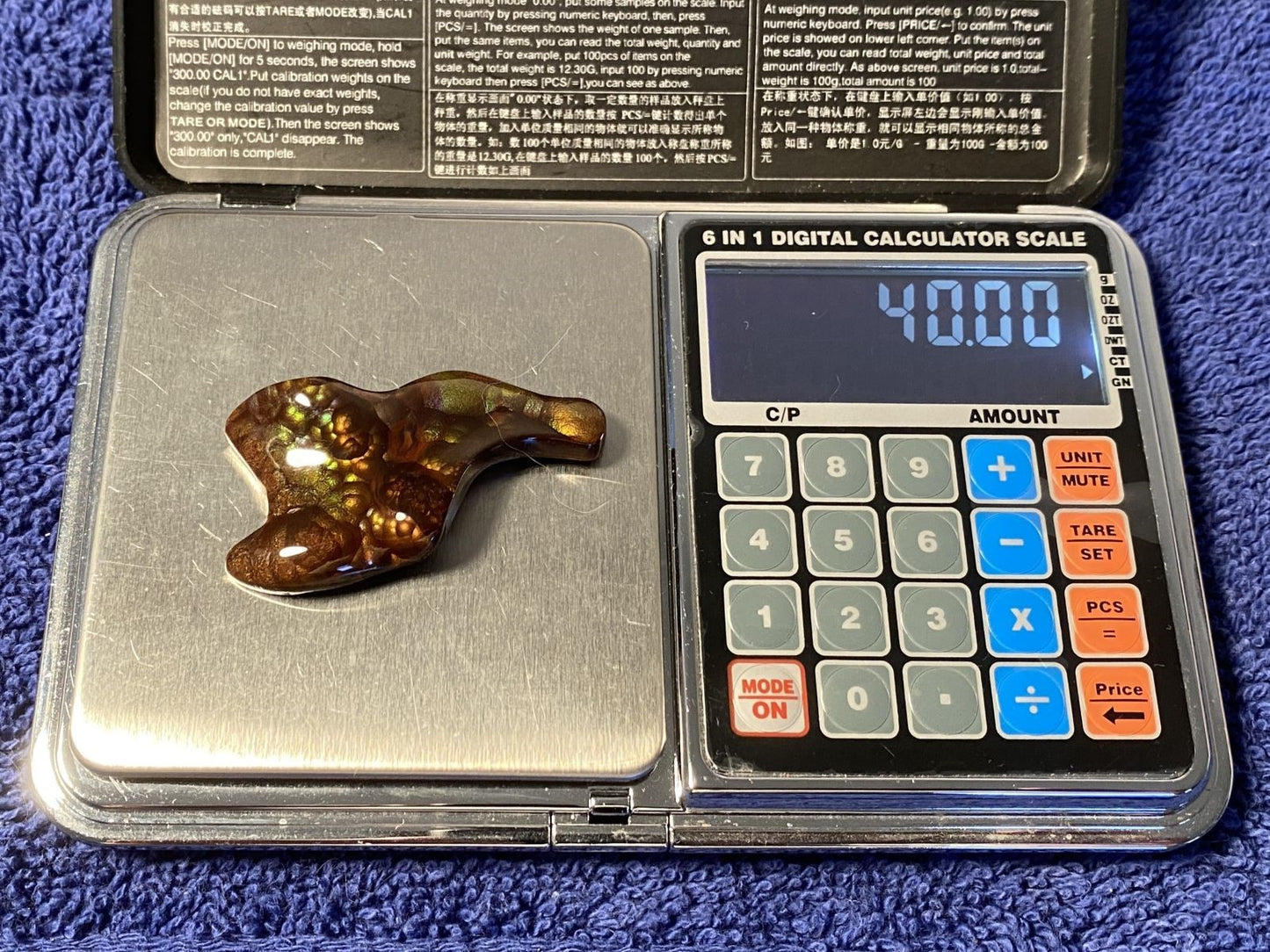 Deer Creek fire agate gemstone on a digital calculator scale with a blue background