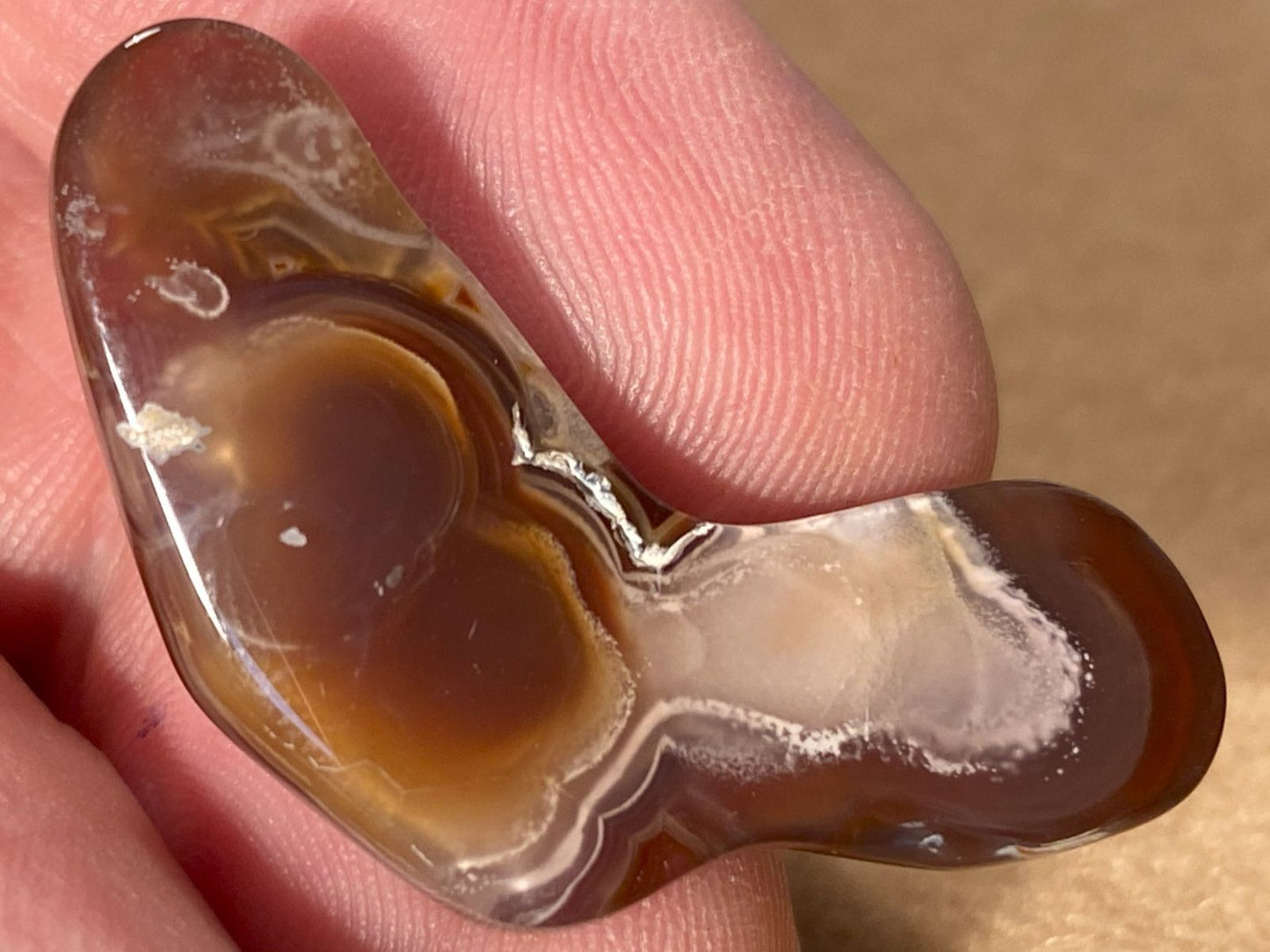 Bottom of fire agate stone held between fingers with a blurred background