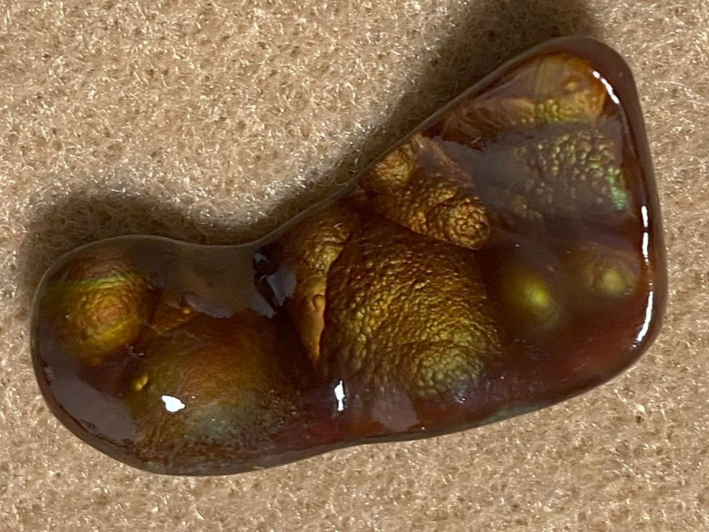 Deer Creek Fire Agate Gemstone with textured surface on a sandy background