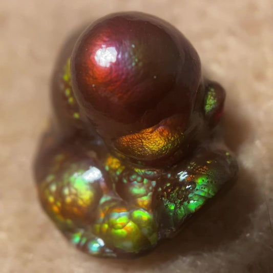Close-up of a colorful Deer Creek iridescent Fire Agate Gemstone Thumbnail Mineral Specimen on a beige background