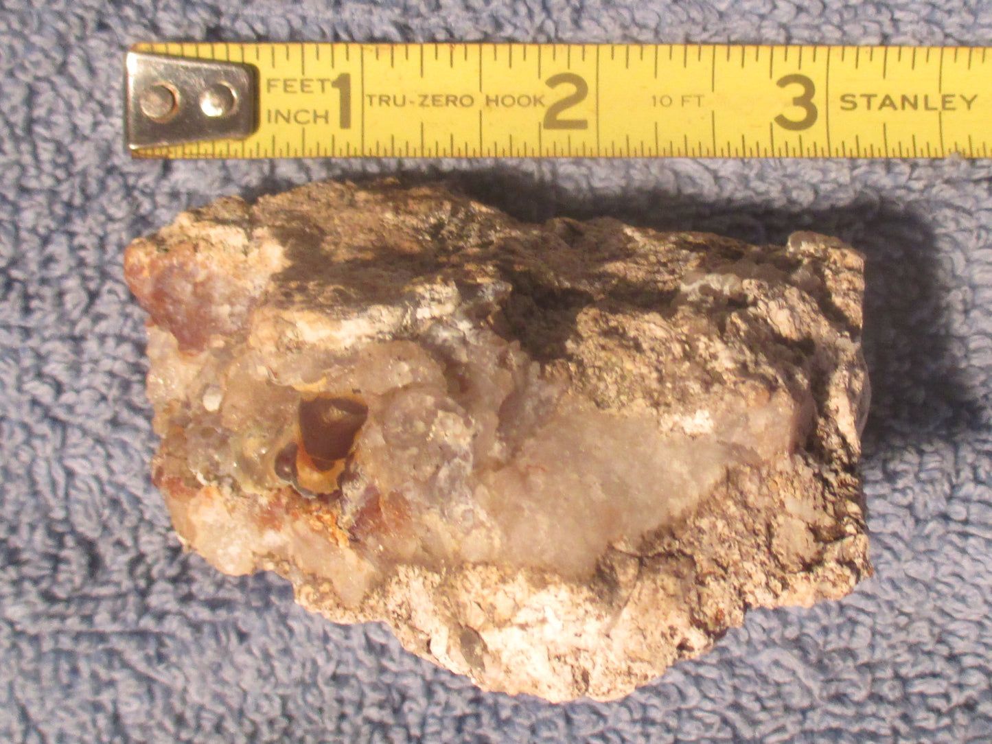 Deer Creek Fire Agate Gemstone Mineral Specimen with a Stanley ruler for scale on a textured surface