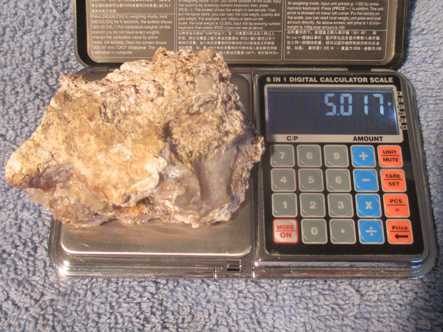 Deer Creek Fire Agate Gemstone Mineral Specimen on a digital calculator scale with a blue background