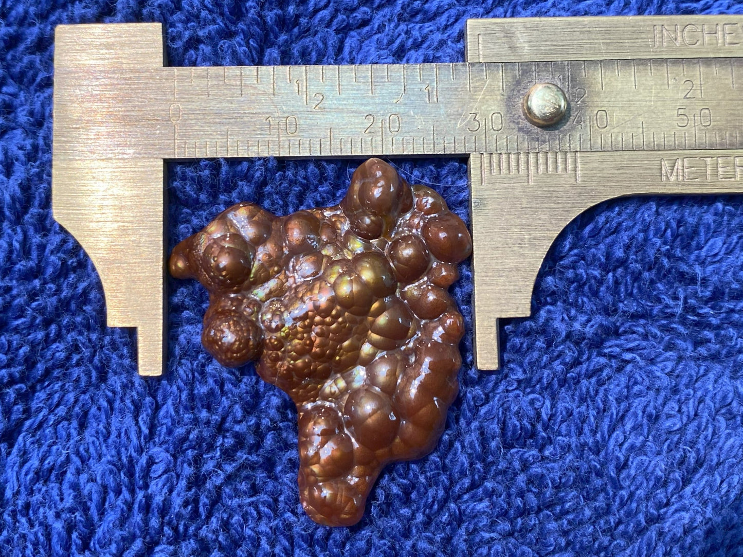Deer Creek Fire Agate Gemstone Mineral Specimen with a ruler on a blue textured background