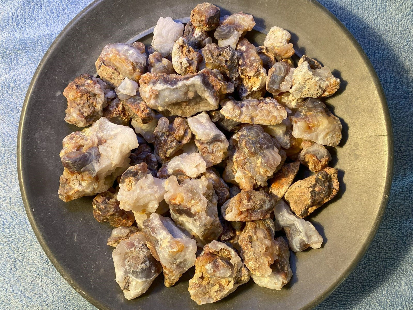 Collection of rough stones on a dark plate with a light blue textured background
