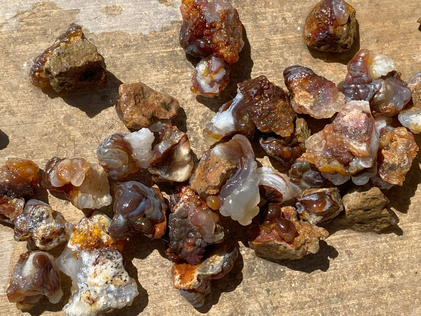 Collection of Deer Creek fire agate rough stones on a wooden surface