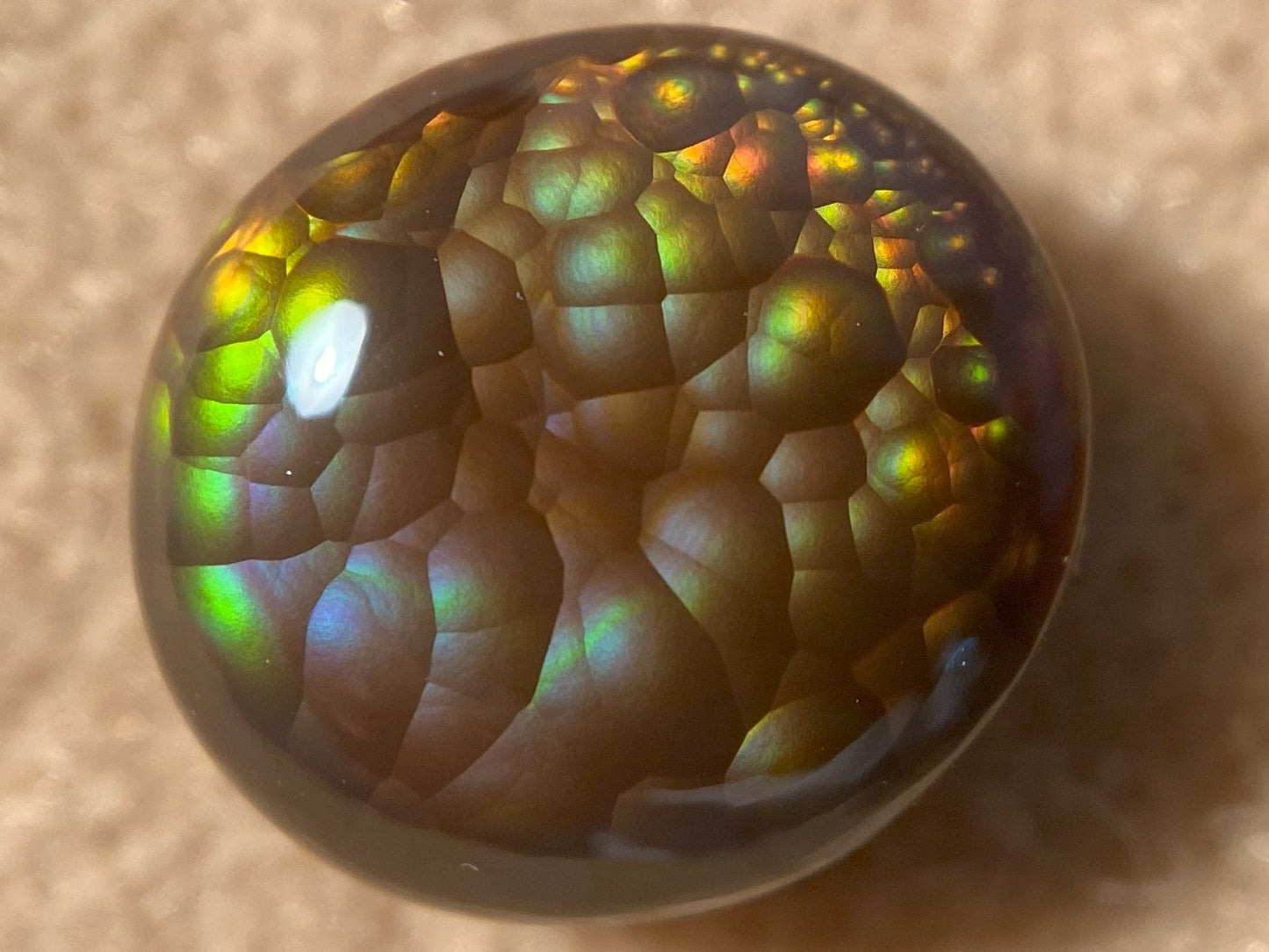 Multicolored Aguascalientes Fire Agate Gemstone with a textured surface on a beige background