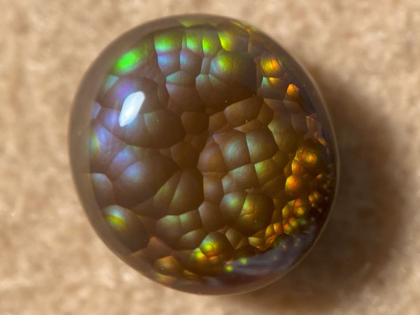 Multicolored iridescent Aguascalientes Fire Agate Gemstone on a beige background