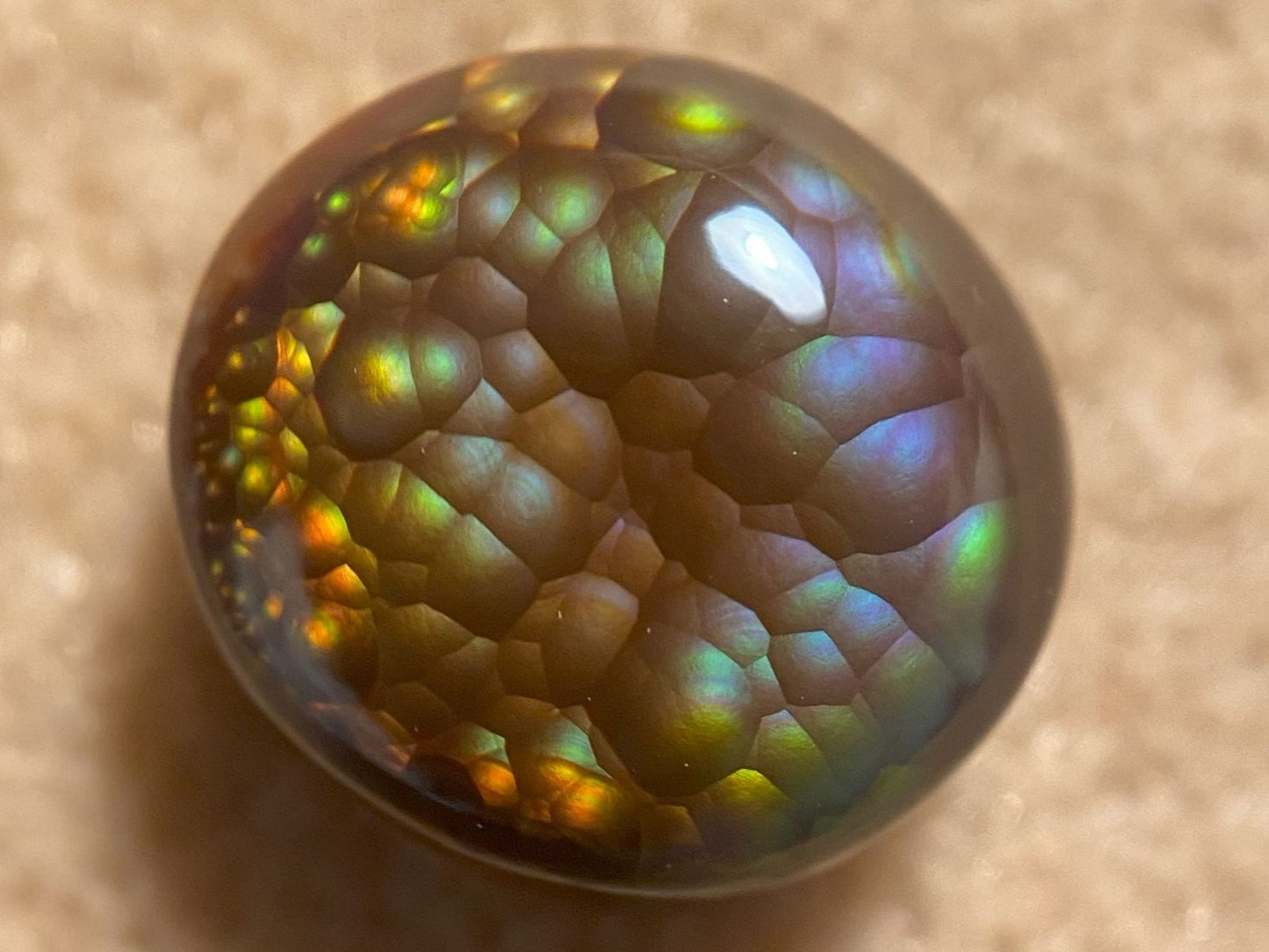 Close-up of a Aguascalientes Fire Agate Gemstone with multicolored patterns on a beige background