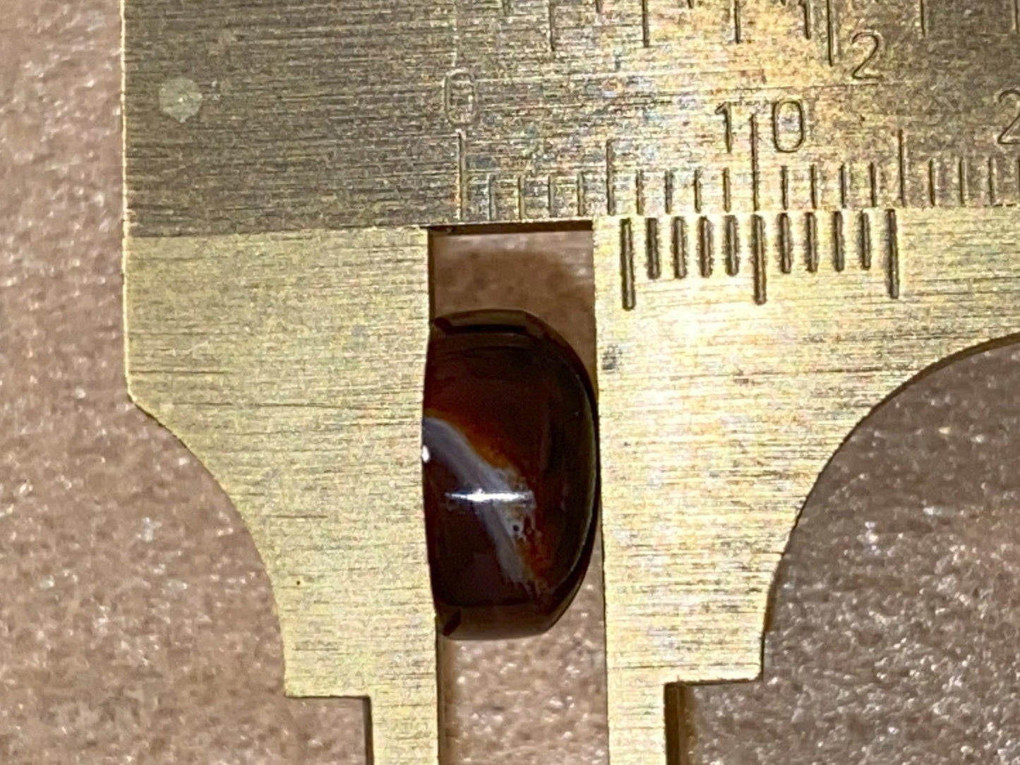 Close-up of a side view of a Aguascalientes Fire Agate Gemstone being measured with a vernier caliper.