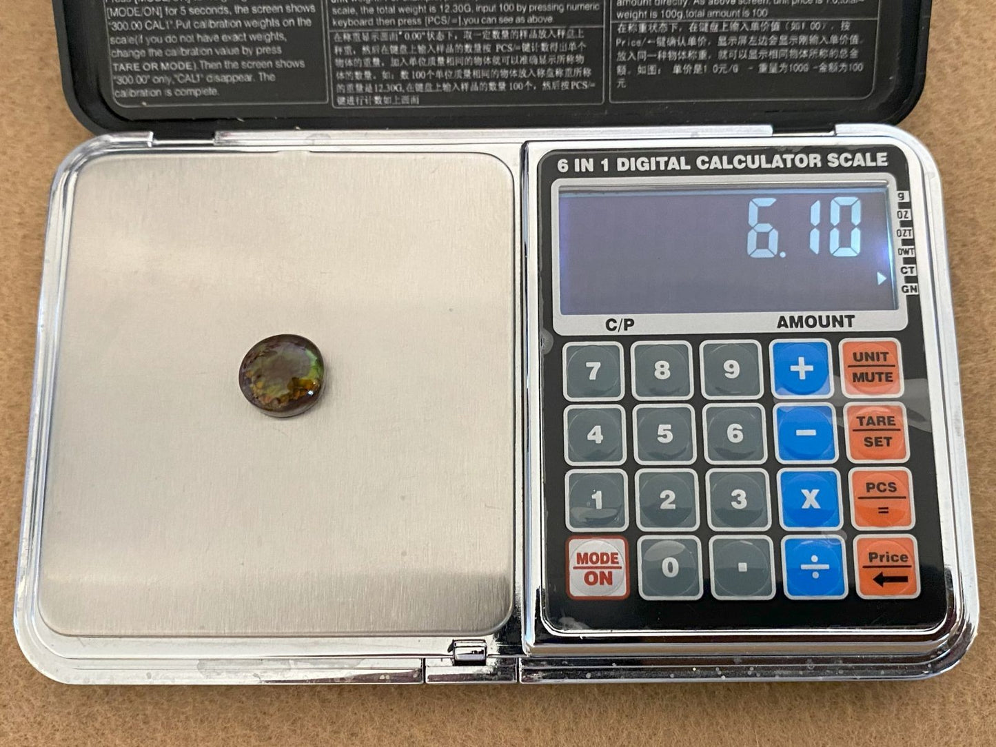 Digital calculator scale with a Aguascalientes Fire Agate Gemstone on top, showing weight reading.