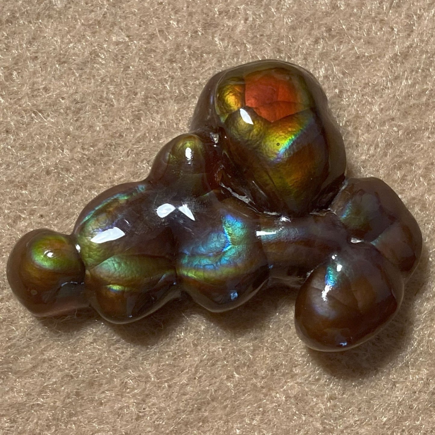 Iridescent Aguascalientes Fire Agate Gemstone on a beige background