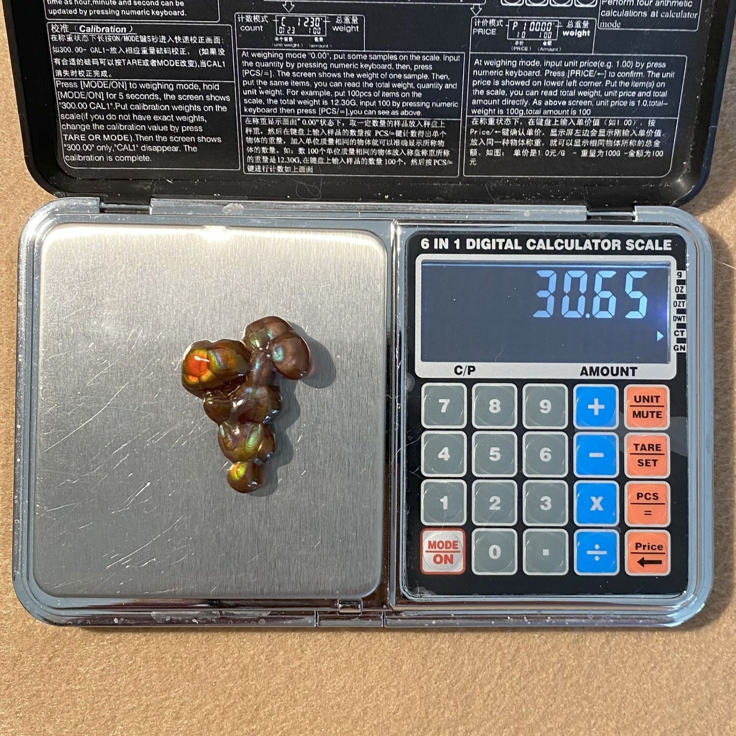 A Aguascalientes Fire Agate Gemstone on a digital calculator scale displaying a weight of 30.65 carats.