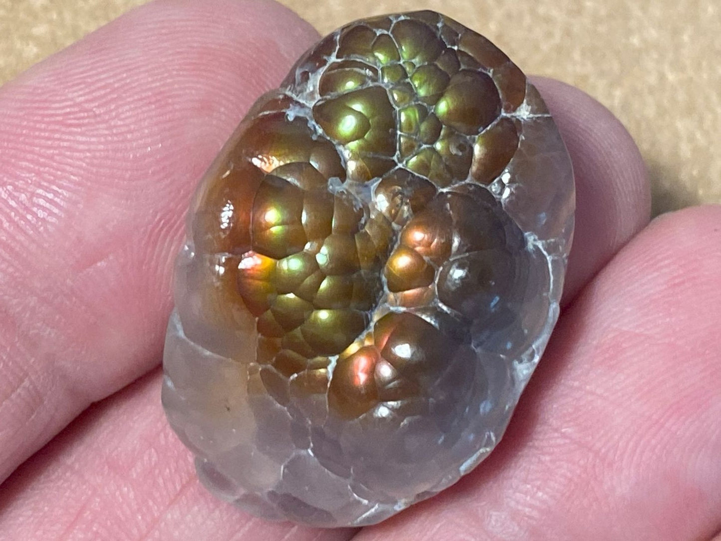 Close-up of a colorful fire agate stone held between fingers