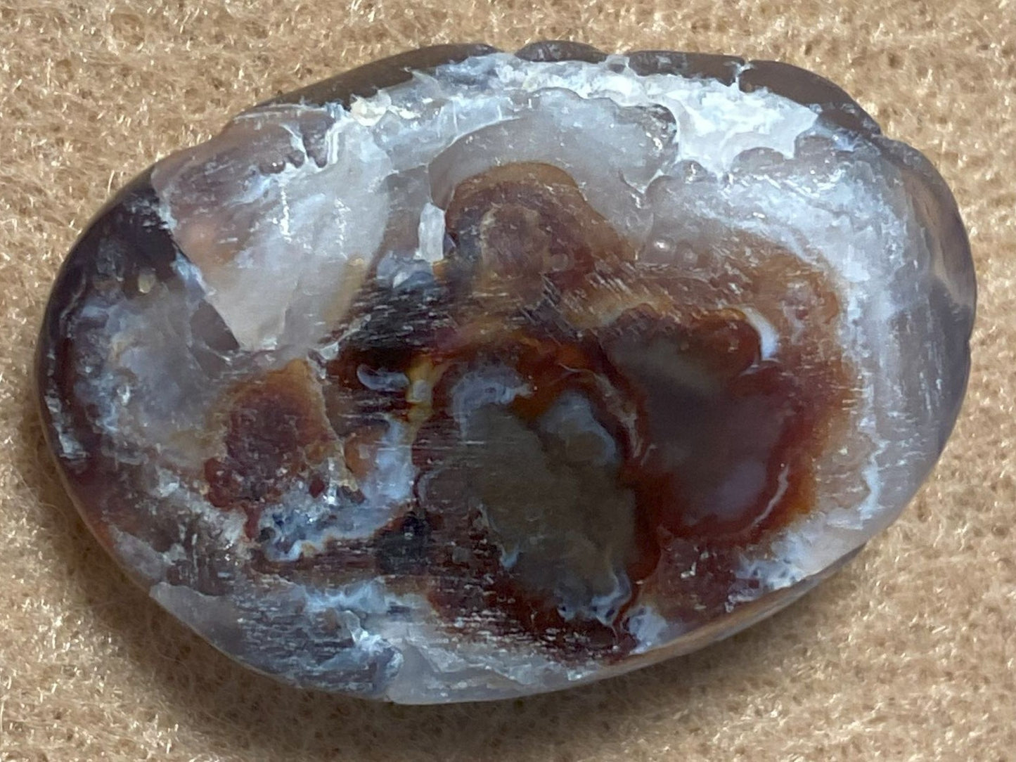 Oval-shaped stone with brown and white patterns on a beige background