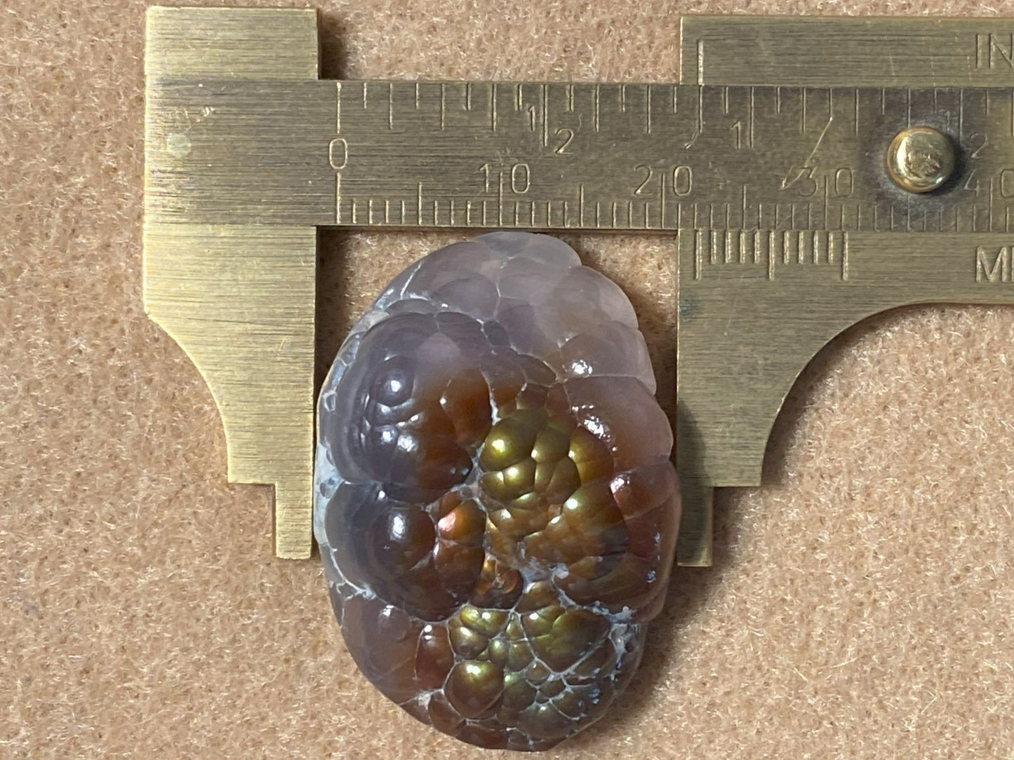 Measuring a polished gemstone with a vernier caliper on a brown background