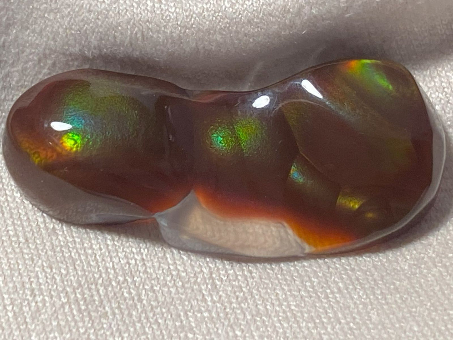 Aguascalientes fire agate gemstone on a textured white background
