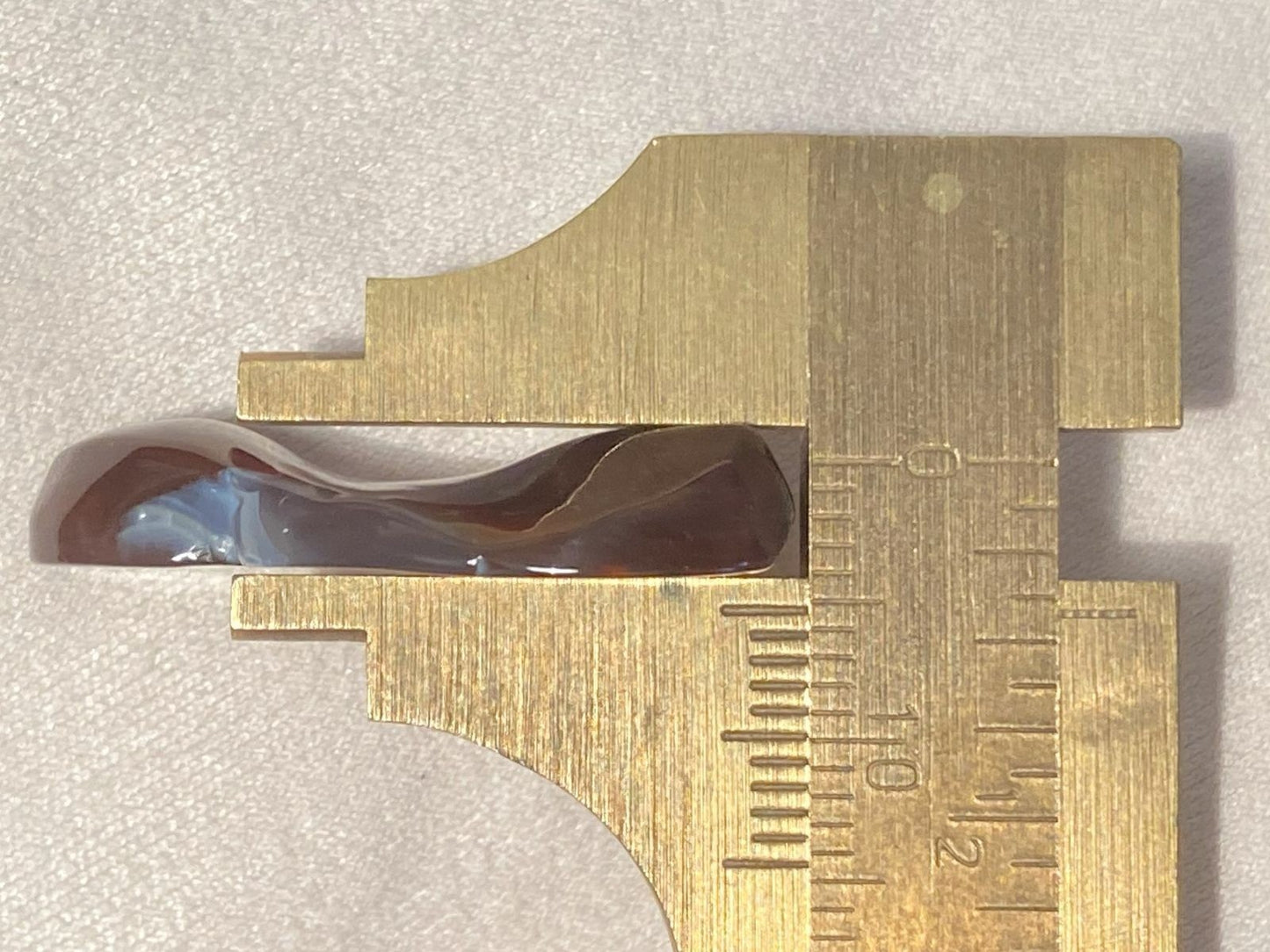 Metallic square ruler with measurement markings on a light gray background