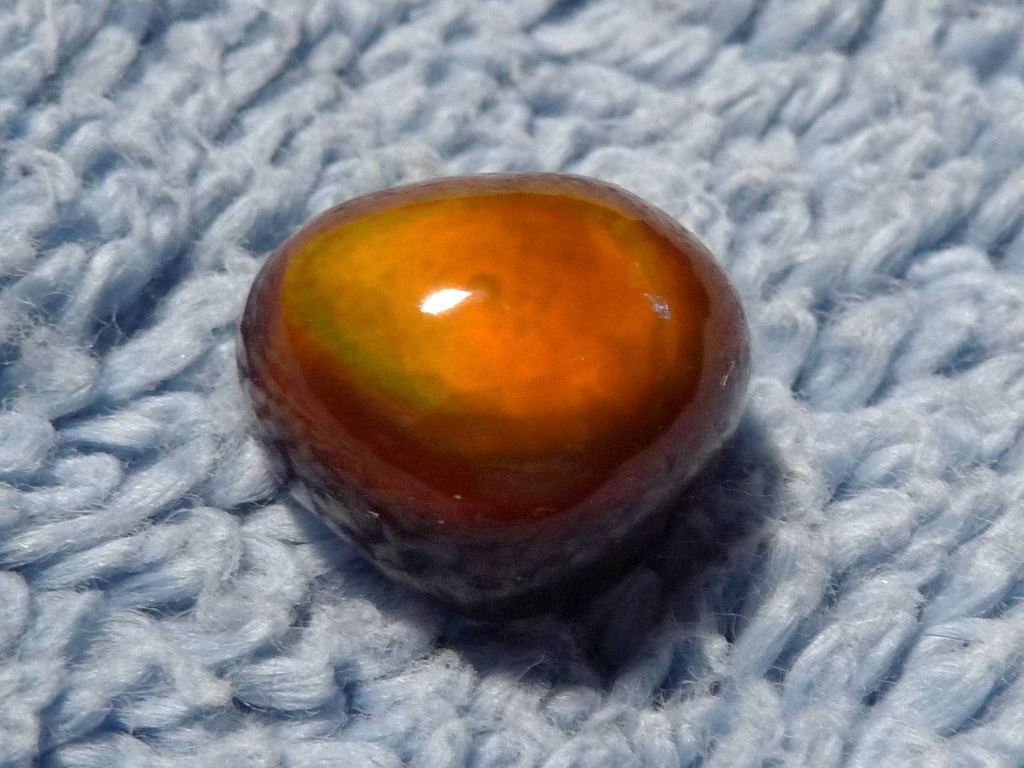 Heart-shaped Slaughter Mountain Fire Agate Gemstone on a textured blue fabric background