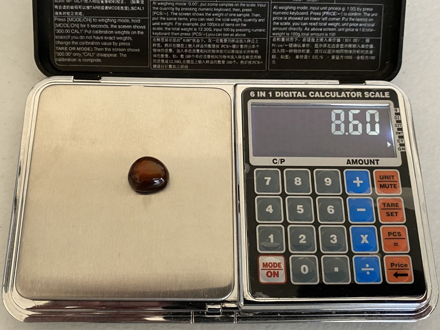 Digital calculator scale with a small Slaughter Mountain Fire Agate Gemstone on it
