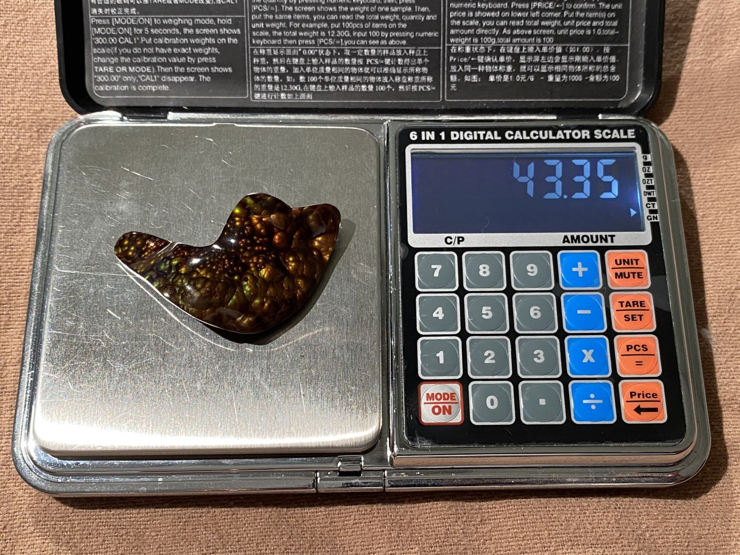 Digital calculator scale with a Slaughter Mountain fire agate gemstone on top