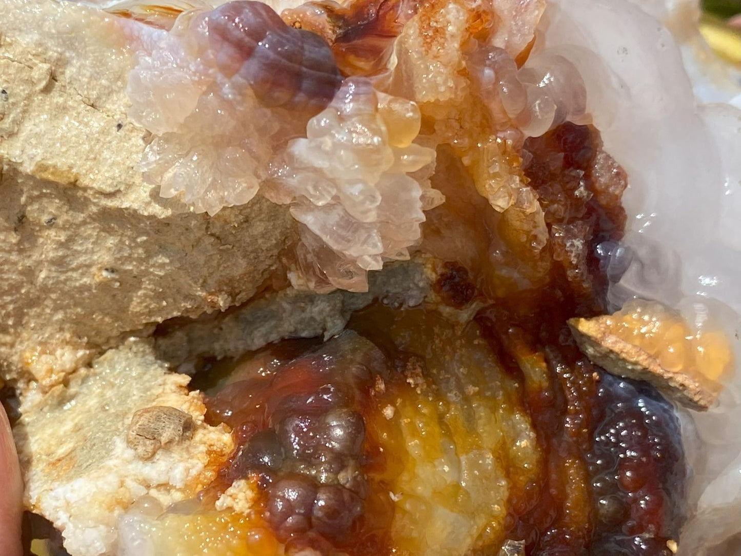 Close-up of fire agate mineral specimen with clear quartz crystals and colored chalcedony formations.