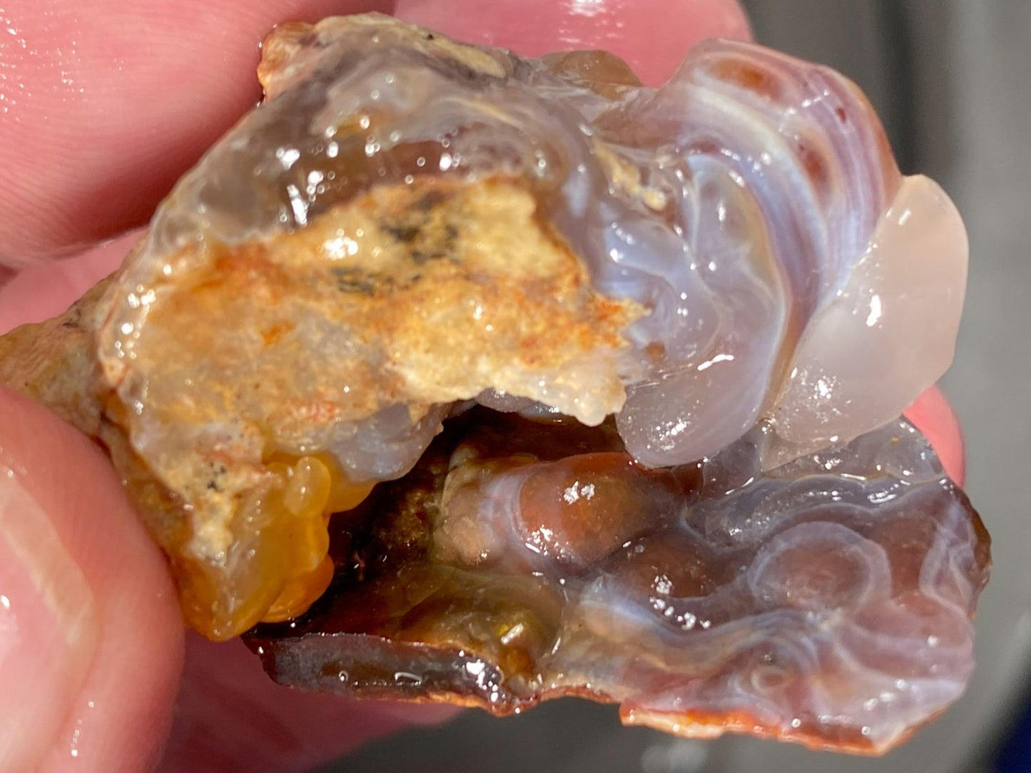 Close-up of a translucent Slaughter Mountain fire agate stone held between fingers