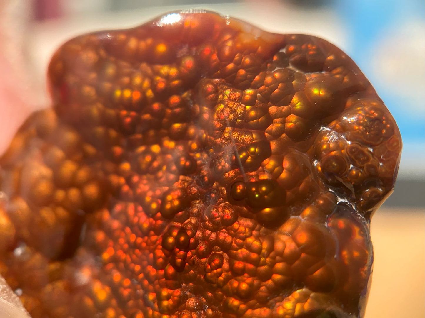 Close-up of a Fire Agate Gemstone held by a hand with a blurred background