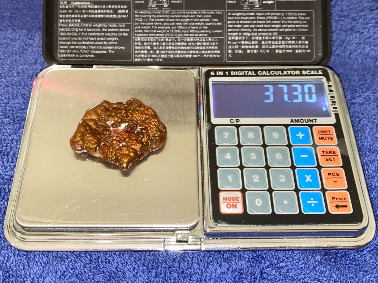 Fire Agate Gemstone on a digital scale with calculator display showing '37.30'