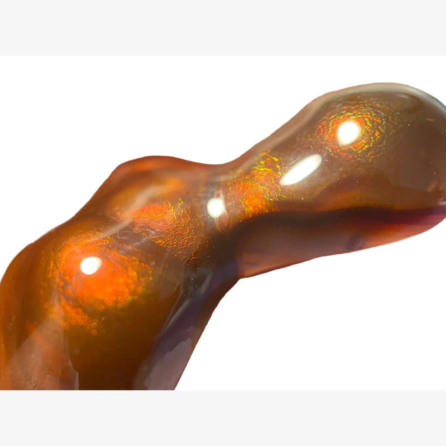 Close-up of a Deer Creek fire agate gemstone showing orange, red and green fire held by a hand.