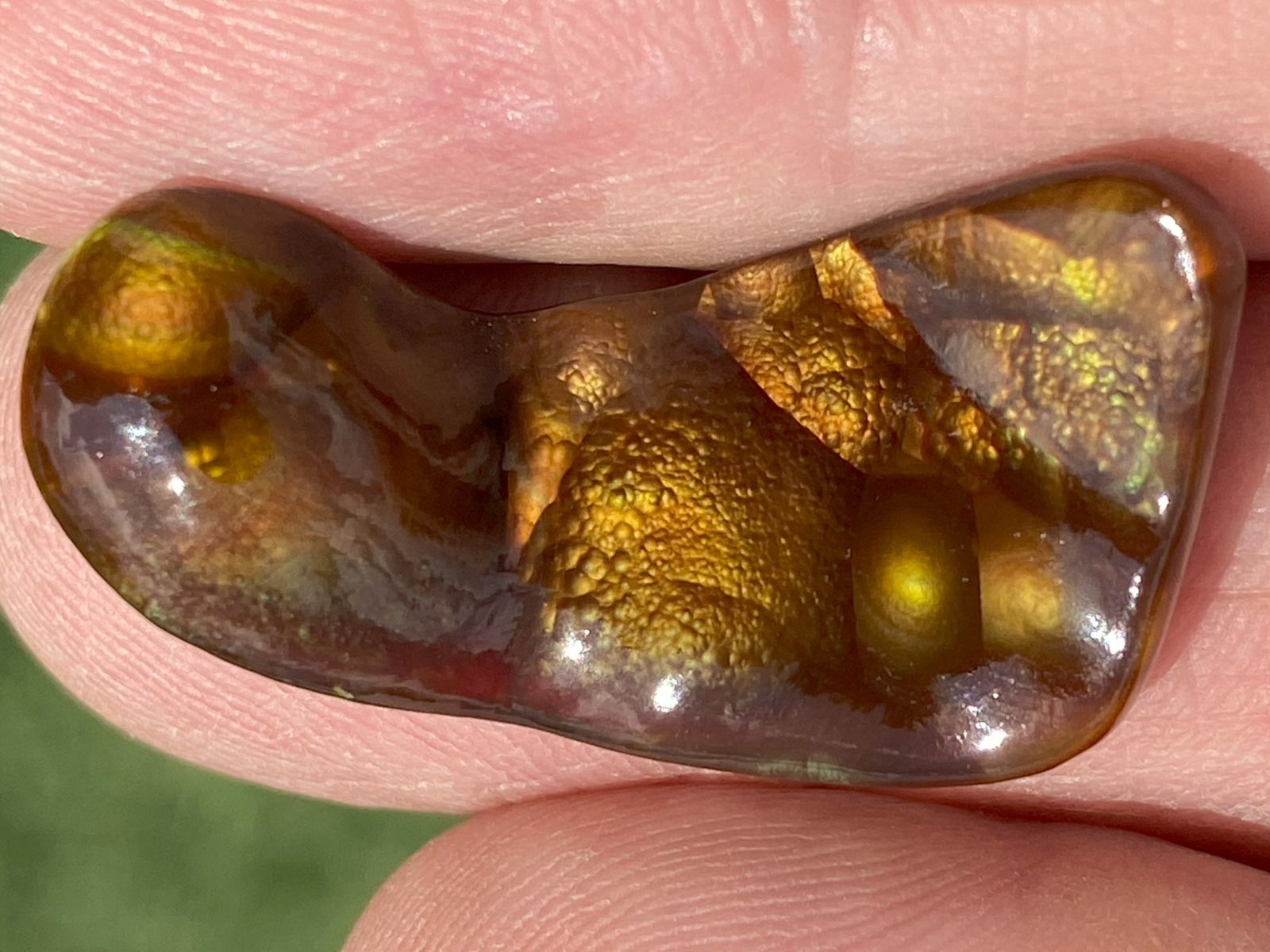 Close-up of a Deer Creek Fire Agate Gemstone held between fingers