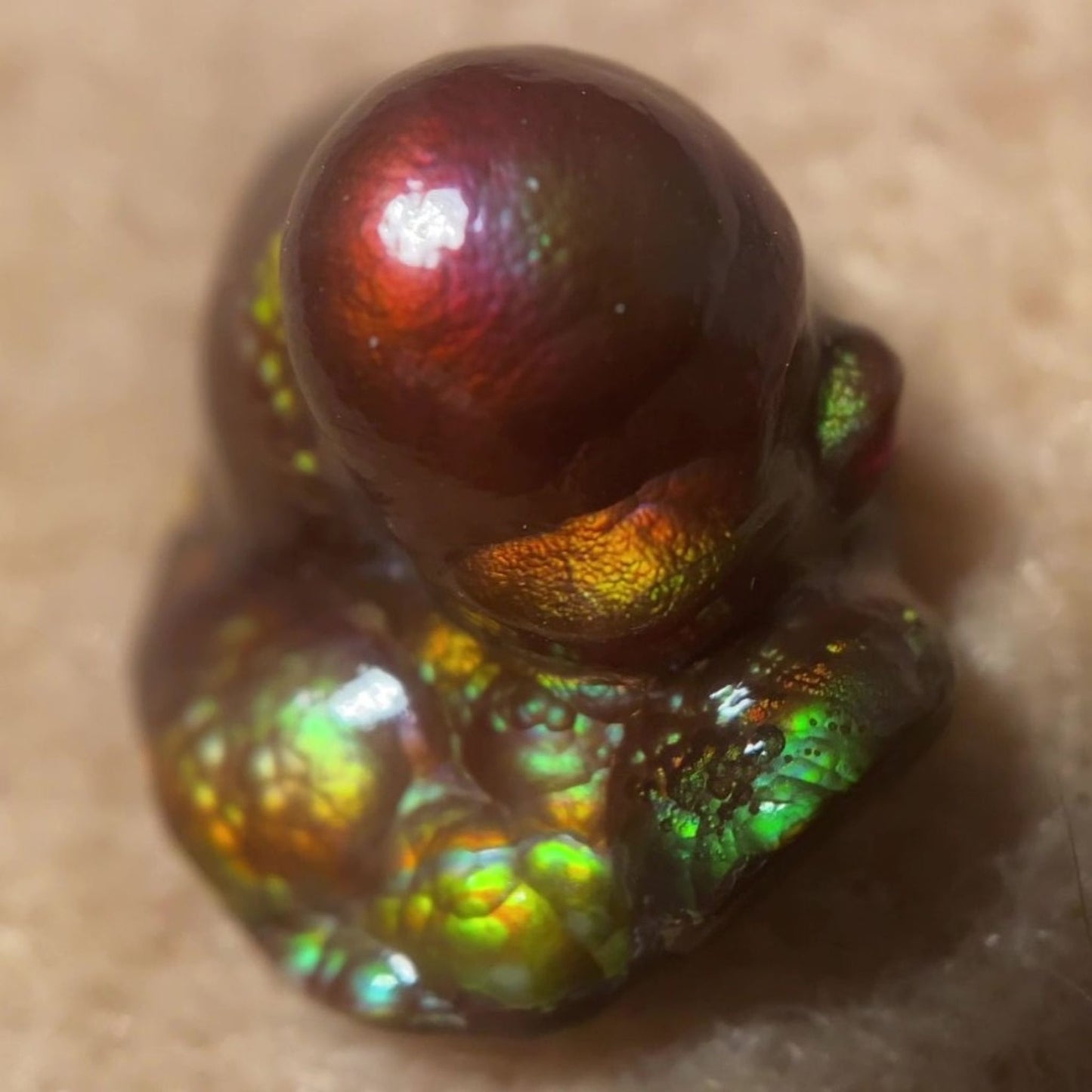 Close-up of a colorful Deer Creek iridescent Fire Agate Gemstone Thumbnail Mineral Specimen on a beige background
