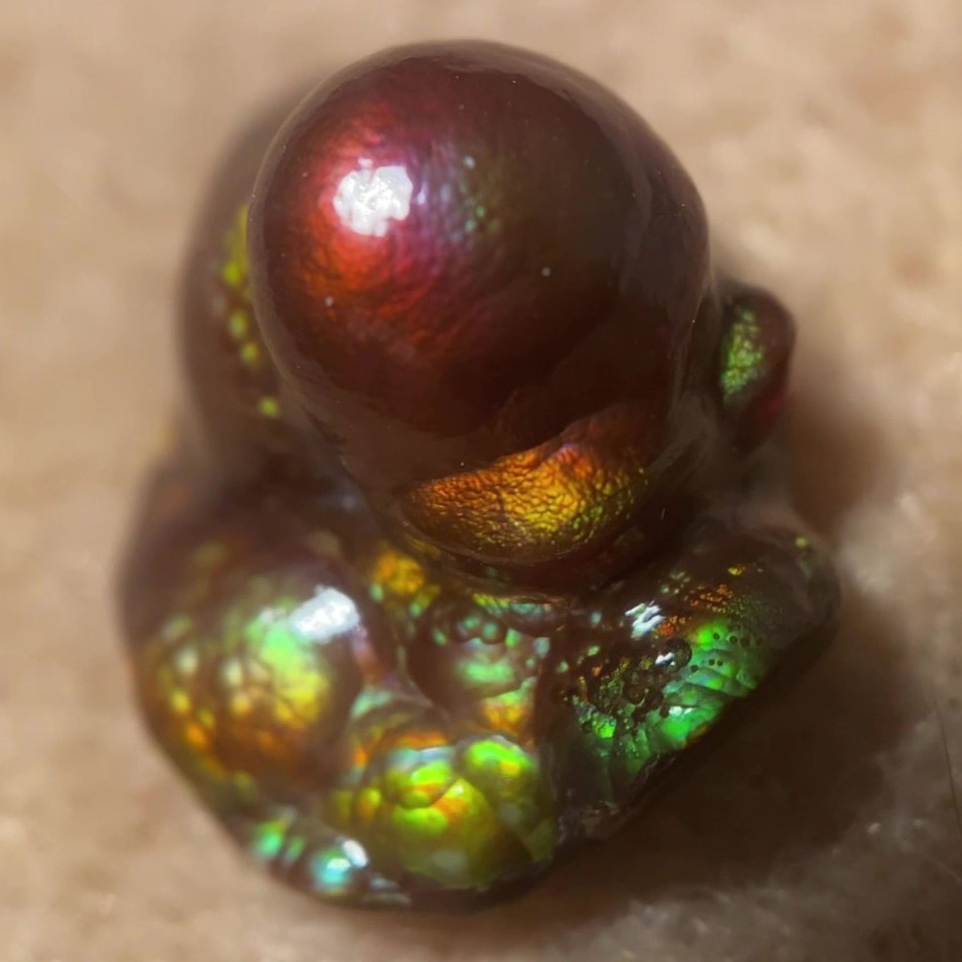 Close-up of a colorful Deer Creek iridescent Fire Agate Gemstone Thumbnail Mineral Specimen on a beige background