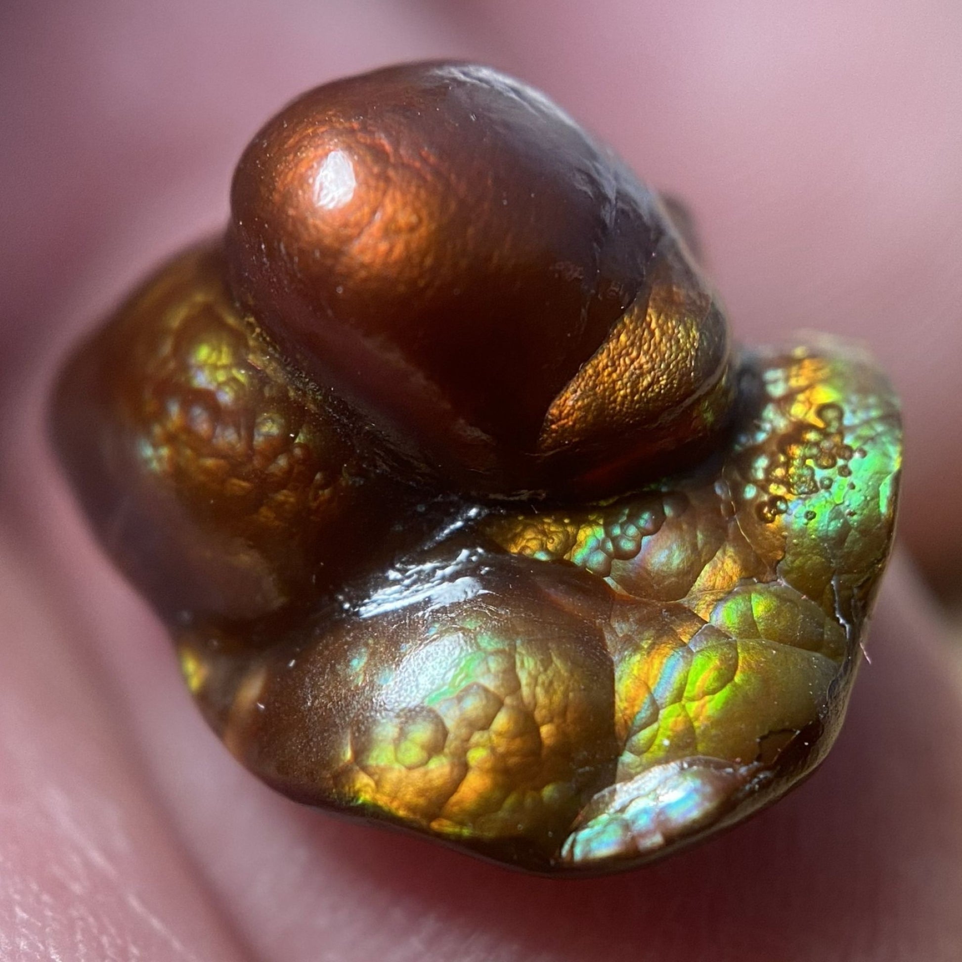 Close-up of a Deer Creek Arizona Fire Agate Gemstone held between fingers