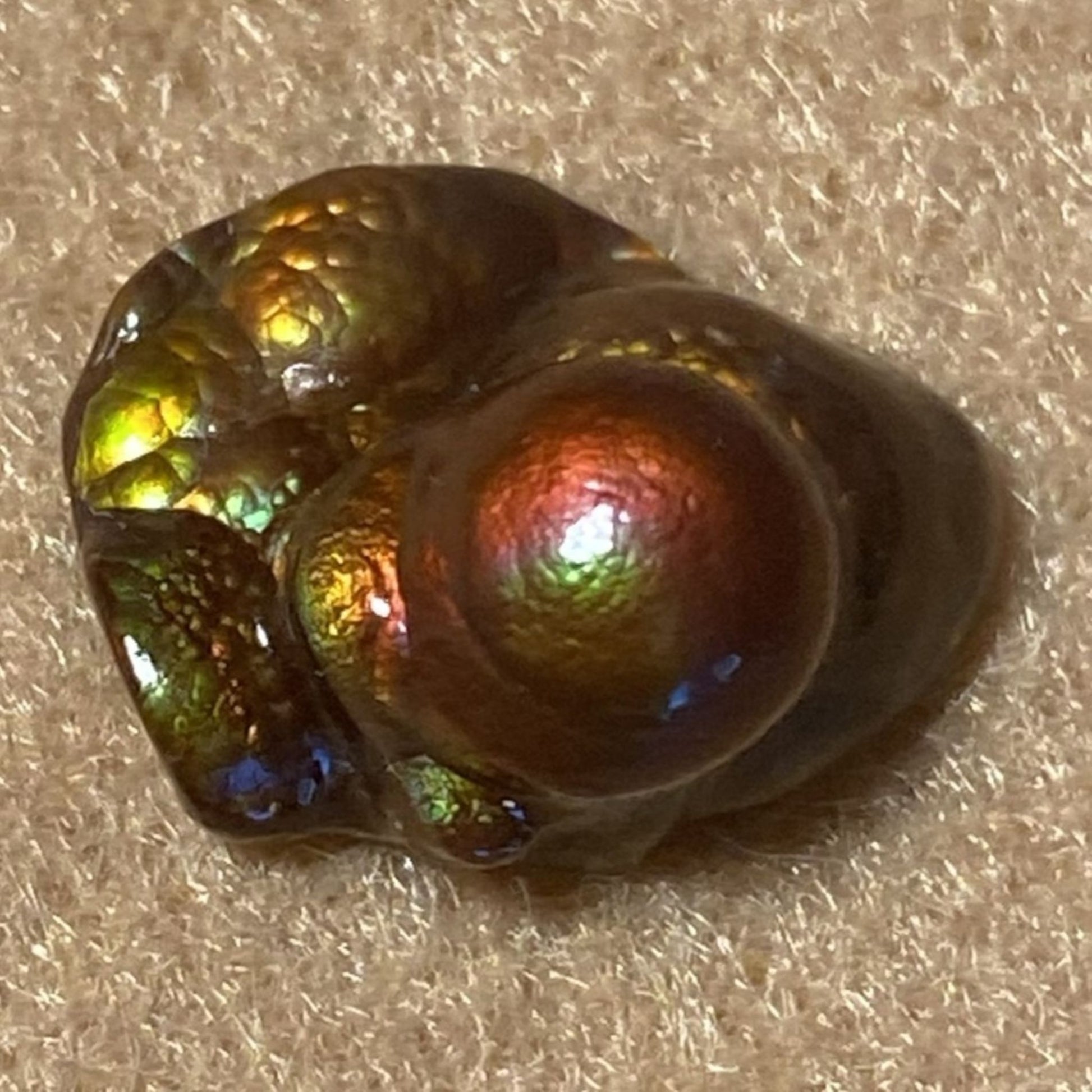 HIgh grade Deer Creek Fire Agate Gemstone Specimen with reflective colors on a textured surface