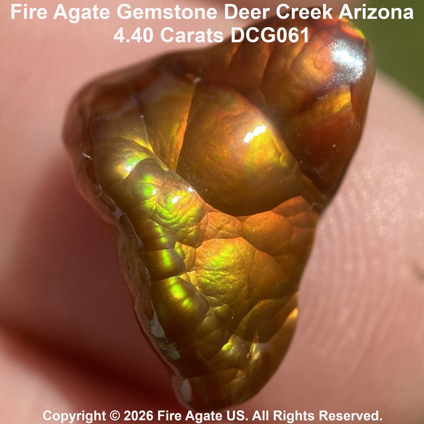 A close-up of a polished fire agate gemstone held against skin, showing warm amber, orange, and iridescent green flashes. Text at the top reads 'Fire Agate Gemstone Deer Creek Arizona'.