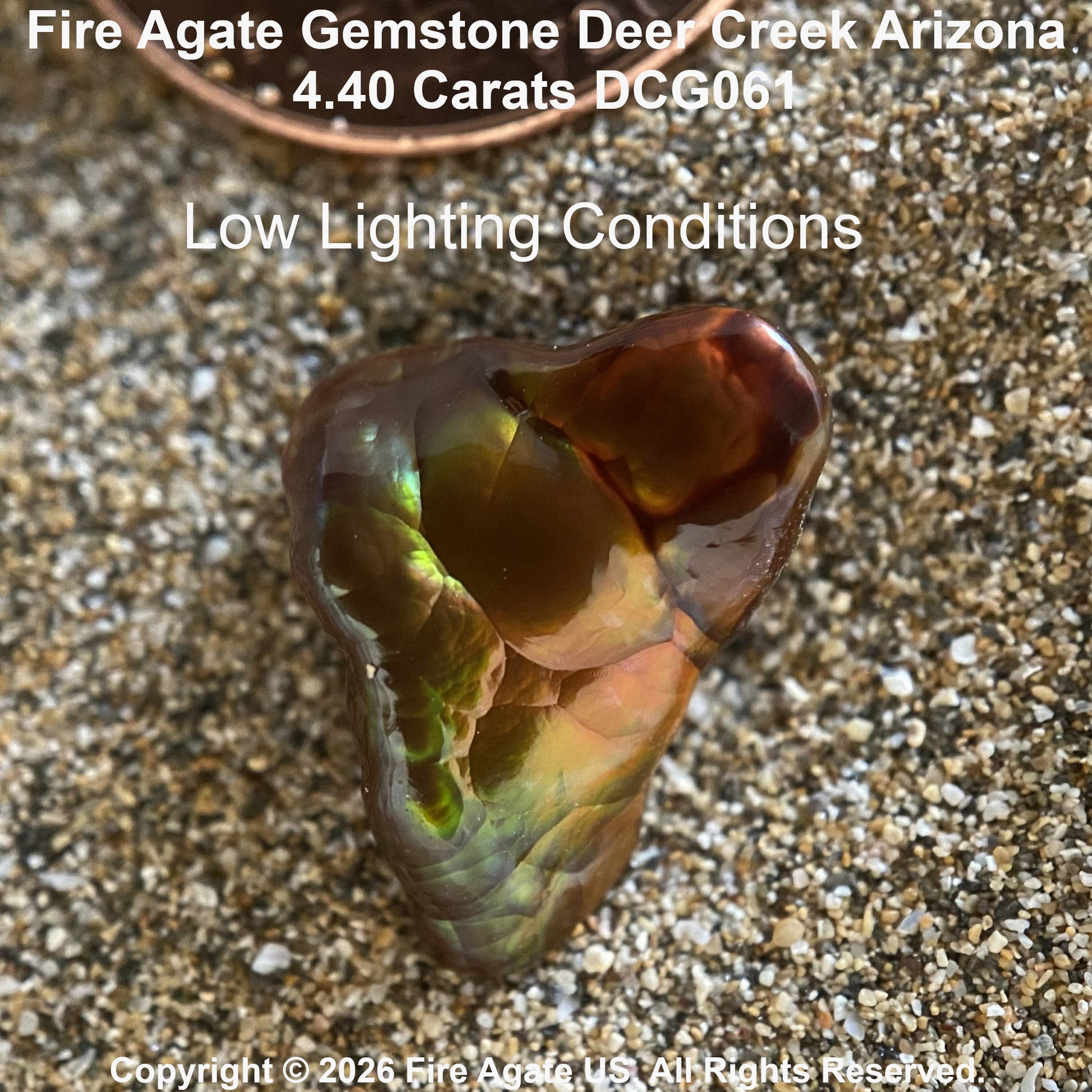 A Fire Agate gemstone with a rich brown body and iridescent green, yellow, and orange flashes, resting on sand. Text overlays display the variety name 'Deer Creek Arizona', carat weight '4.40 carats'.