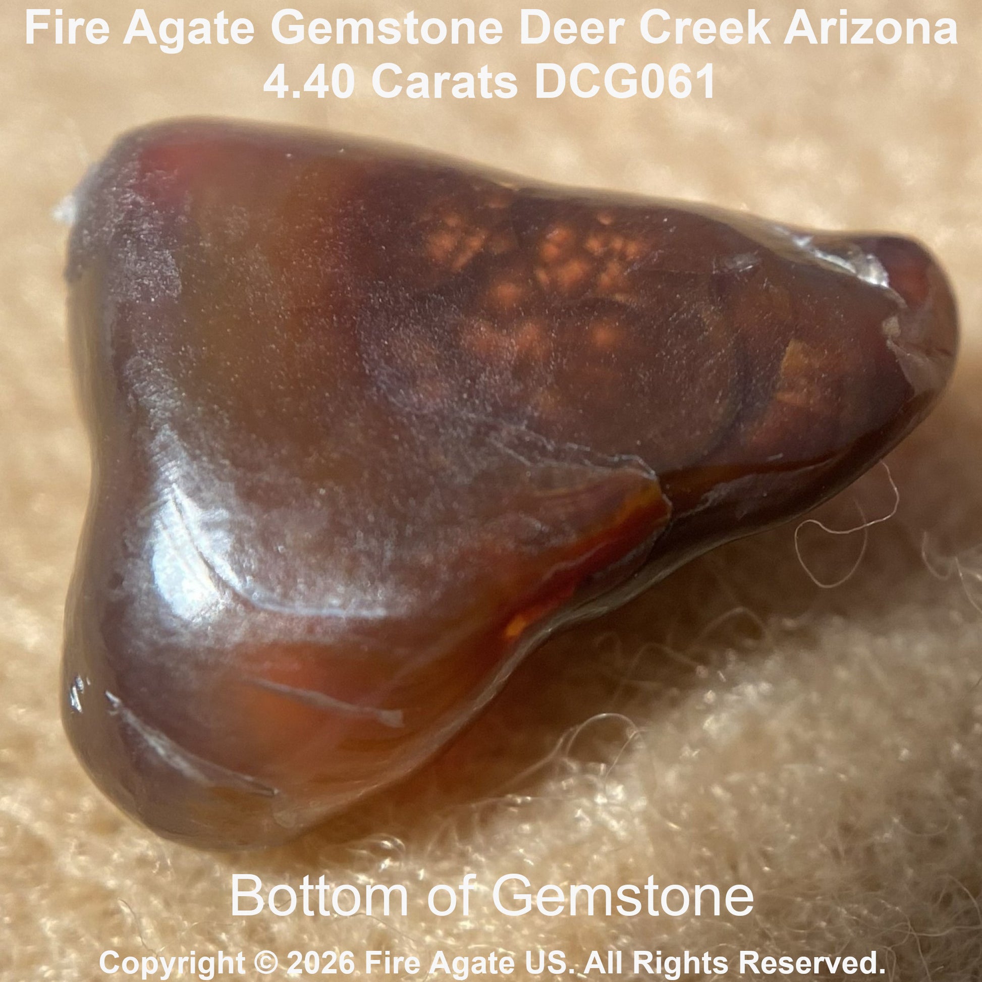 The bottom of a polished fire agate gemstone with a triangular shape, featuring a translucent amber-brown body with orange and reddish inclusions. The top of the stone has text overlay reading 'Fire Agate Gemstone Deer Creek Arizona'.