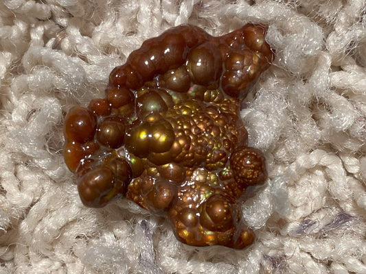 Close-up of a Deer Creek Fire Agate Gemstone Mineral Specimen on a textured white background