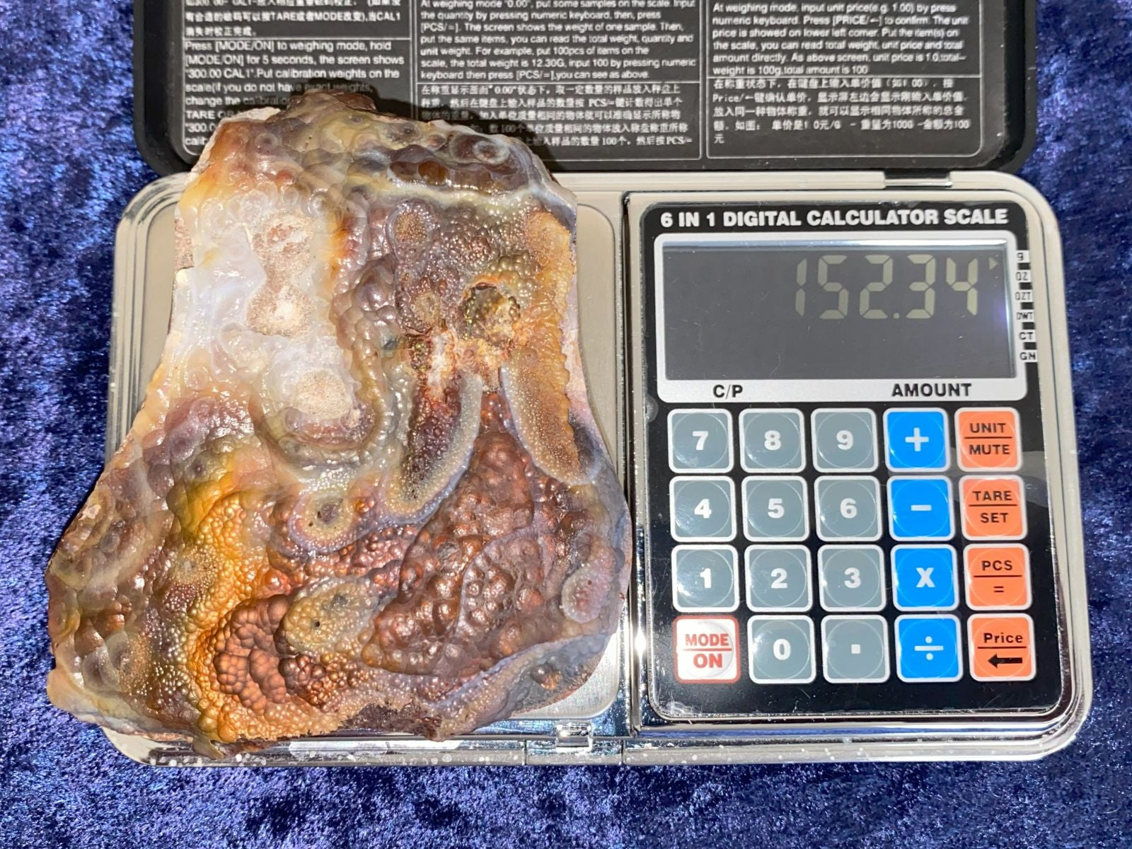 Deer Creek Fire Agate Specimen on a digital calculator scale with a blue textured background