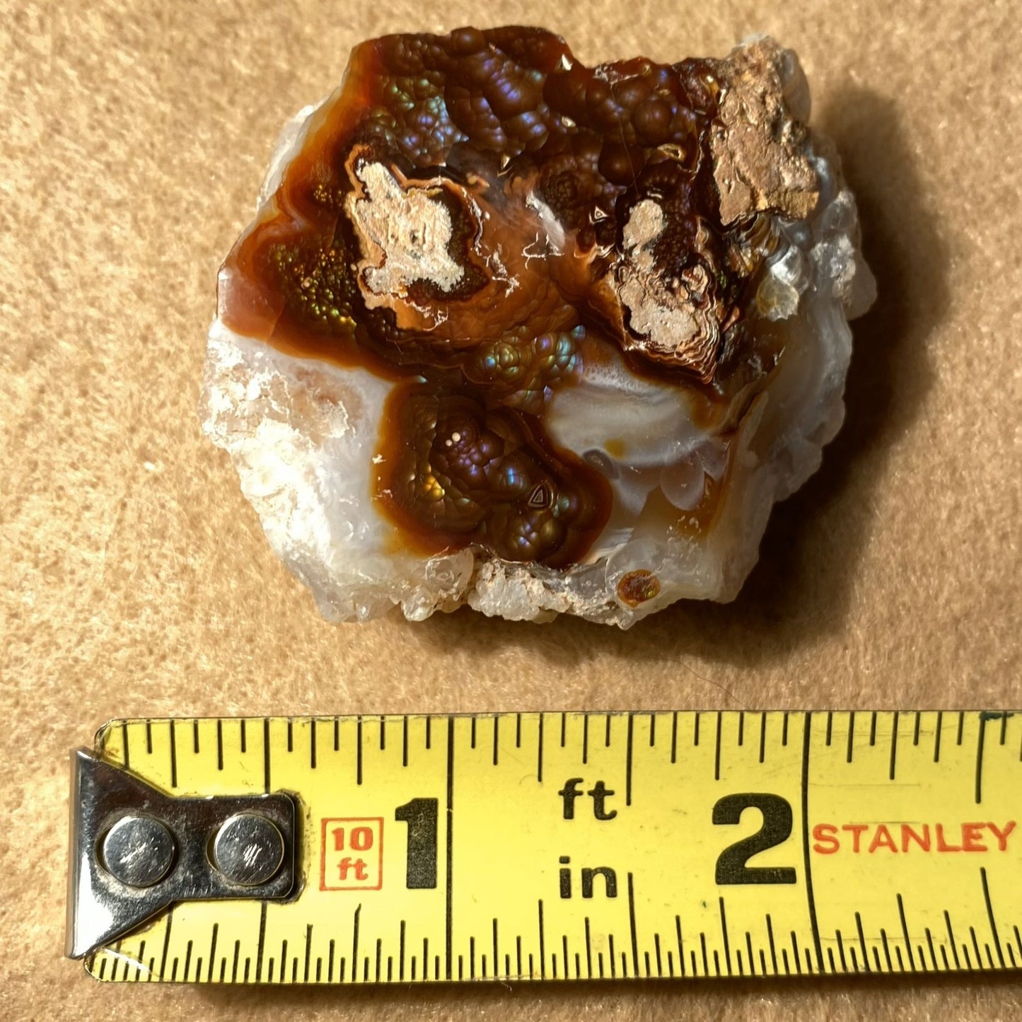 Mineral sample with brown and white colors next to a Stanley measuring tape on a beige background