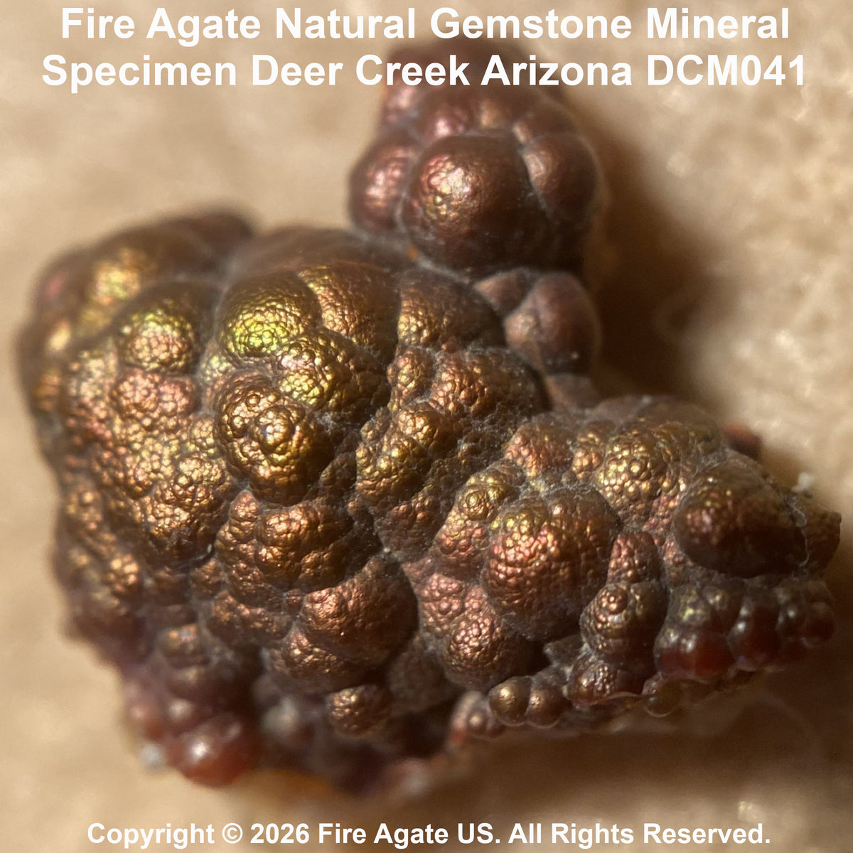 Close-up of a fire agate natural gemstone mineral specimen with a bubbled, metallic copper-brown surface and iridescent green highlights, labeled 'Fire Agate Natural Gemstone Mineral Specimen Deer Creek Arizona DCM041' with copyright text 'Fire Agate US.'.
