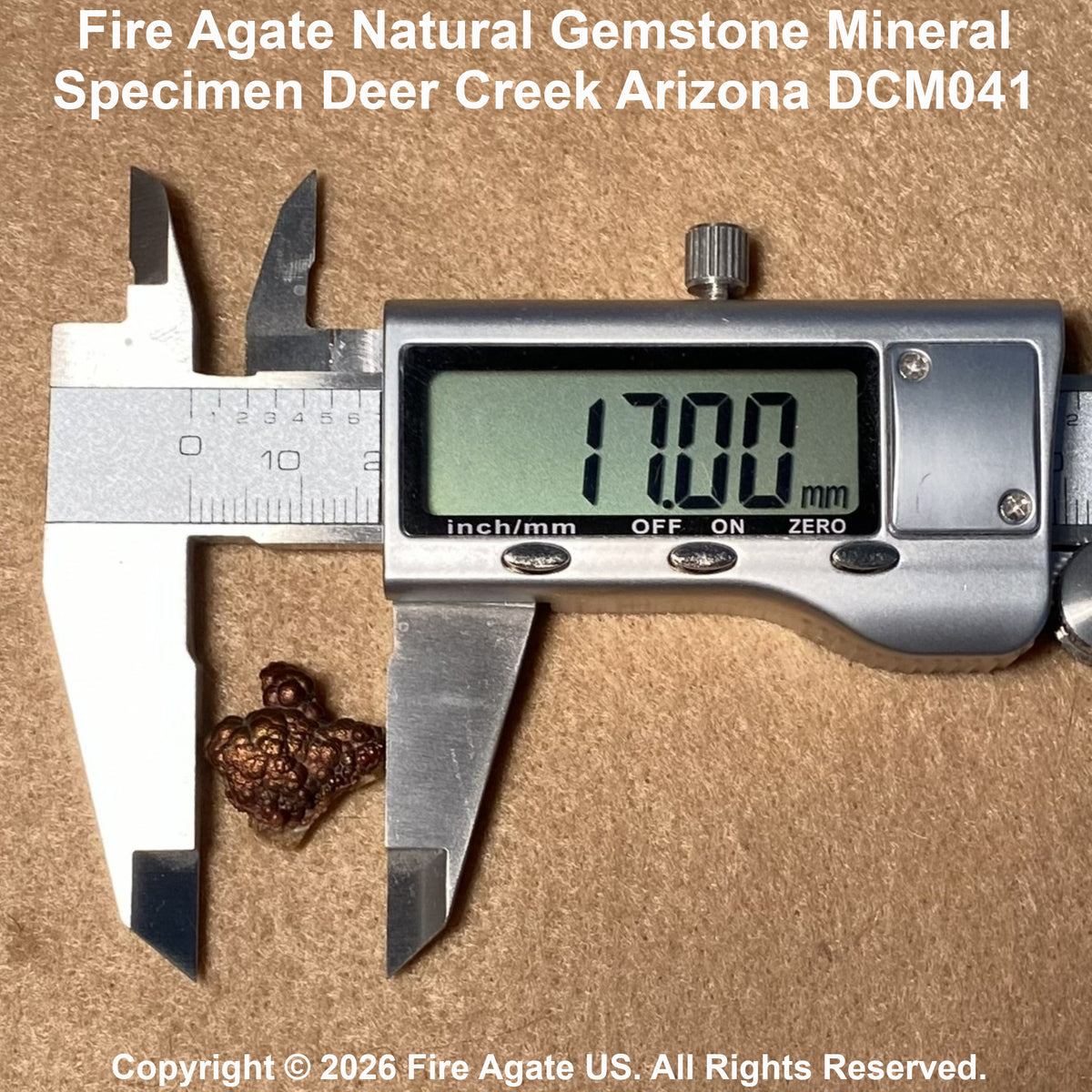 A small brown agate gemstone mineral specimen placed under the jaws of a digital caliper on a tan textured background, with text reading 'Fire Agate Natural Gemstone Mineral Specimen Deer Creek Arizona DCM041' at the top and copyright text at the bottom.