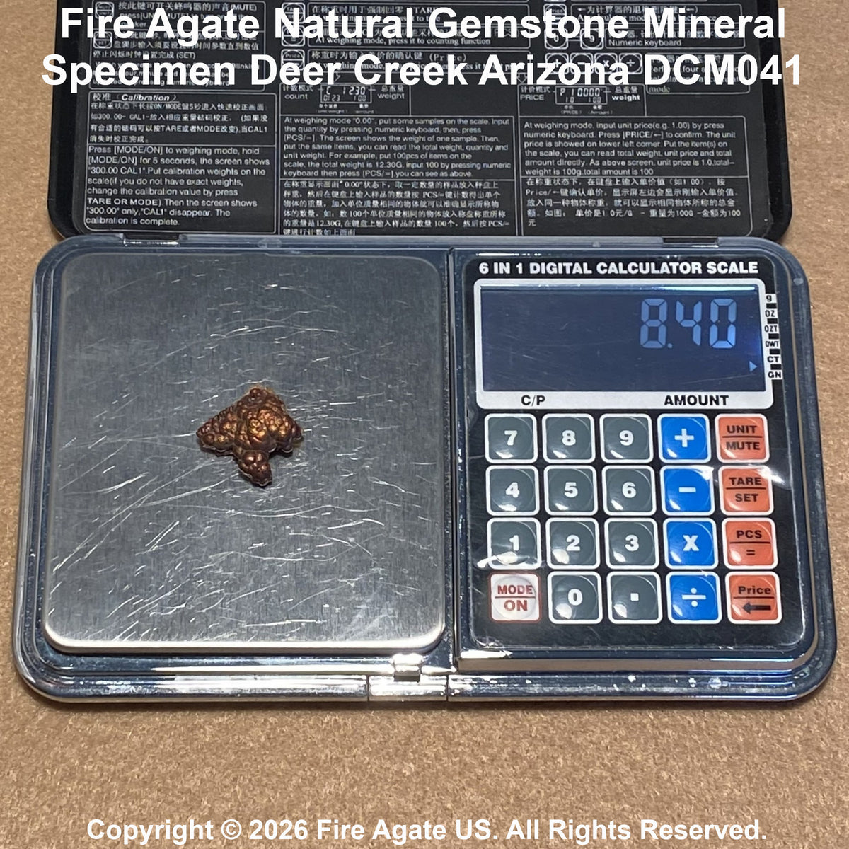 A small brown fire agate gemstone specimen is shown on a digital pocket scale with a calculator face, in front of its black documentation card. Text at the top reads 'Fire Agate Natural Gemstone Mineral Specimen Deer Creek Arizona DCM041'.