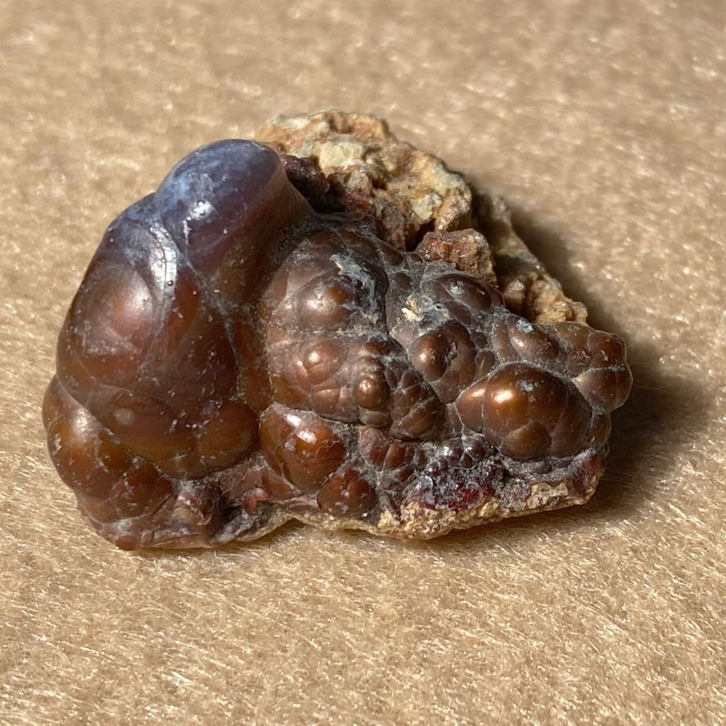Close-up of a brown crystal rock on a beige surface