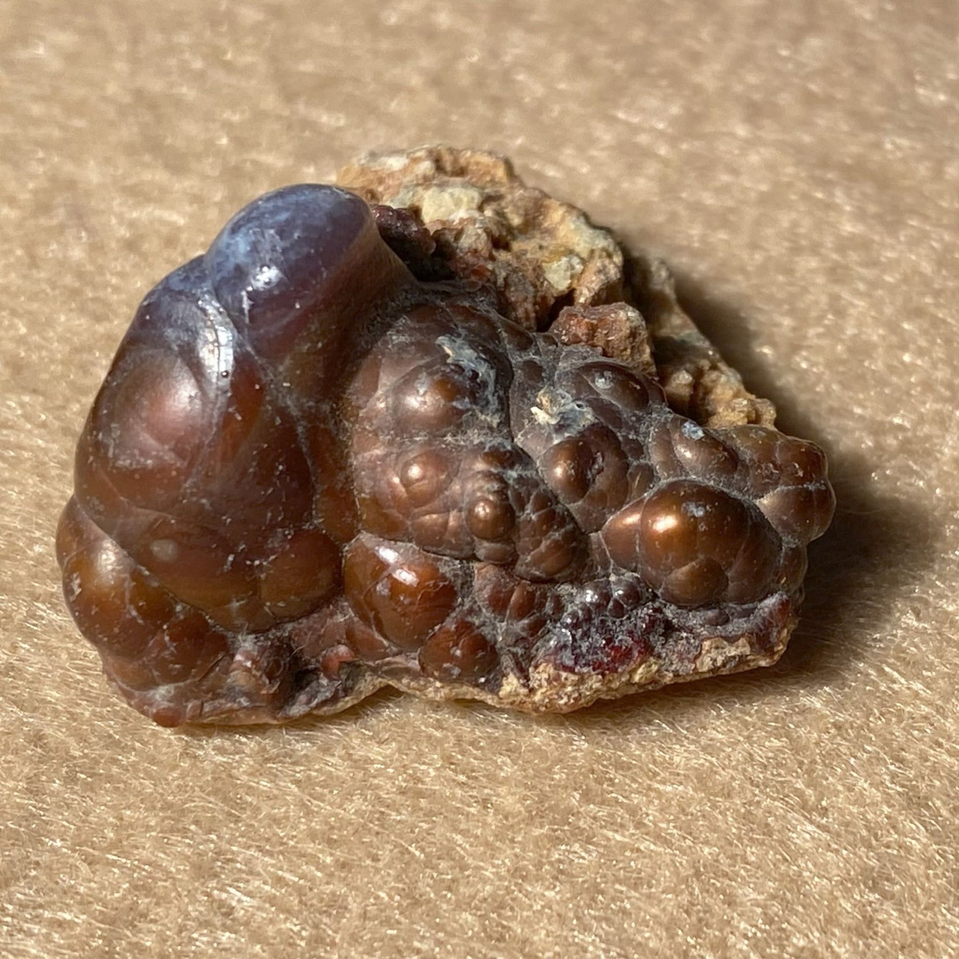 Close-up of a brown crystal rock on a beige surface