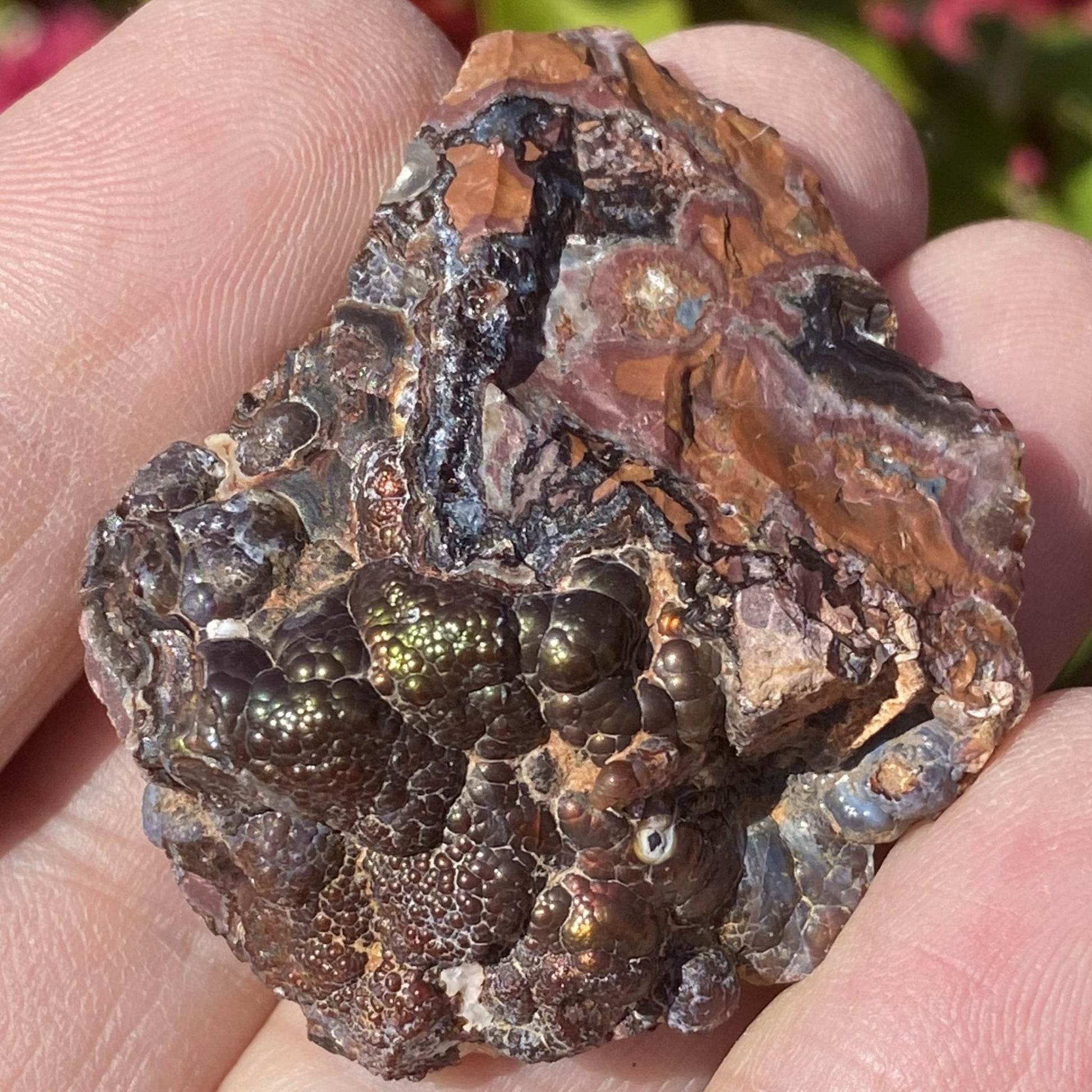 Close-up of a hand holding a rough, brown crystal fire agate rock.