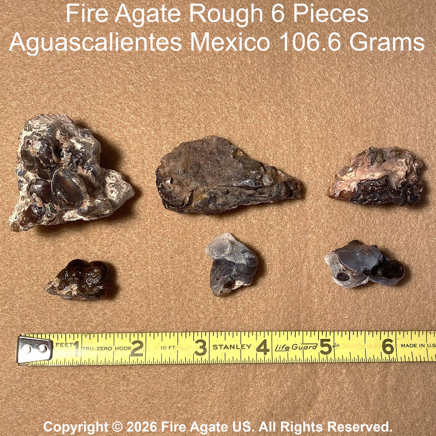 Six pieces of rough fire agate material arranged on a tan textured background with a yellow Stanley tape measure below for scale. Text at the top reads 'Fire Agate Rough 6 Pieces Aguascalientes Mexico 106.6 Grams