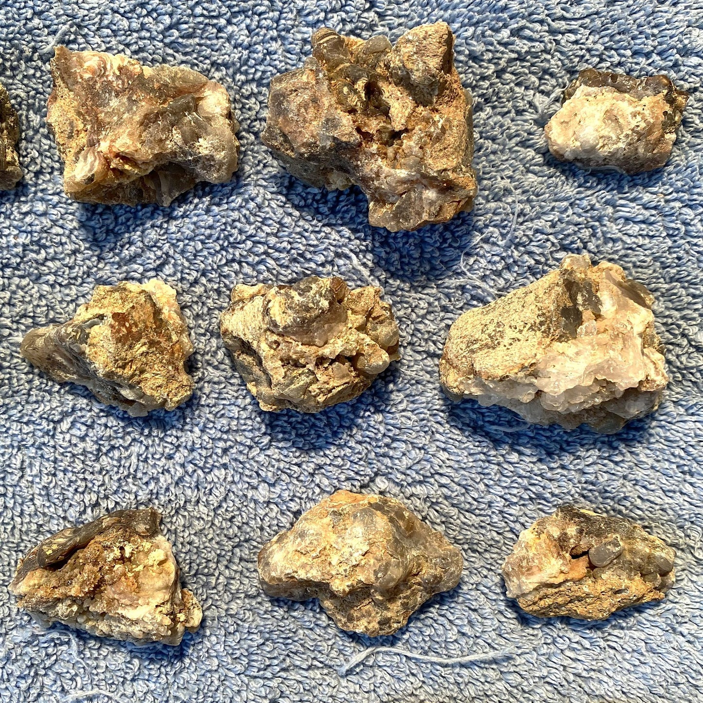 Several rough, irregular natural stone or mineral pieces arranged on a textured blue fabric background.