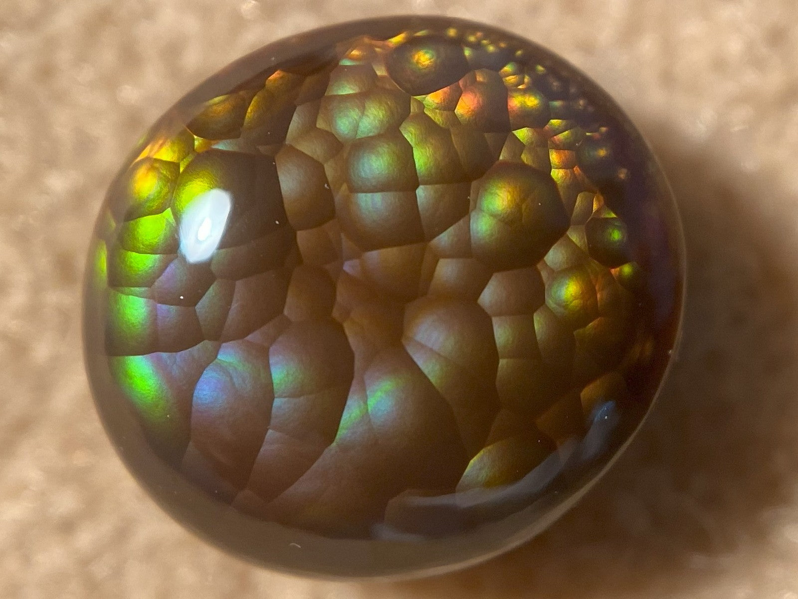 Multicolored Aguascalientes Fire Agate Gemstone with a textured surface on a beige background